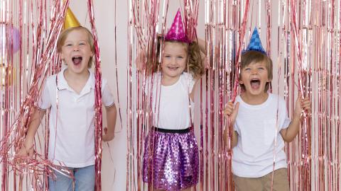 Kids in party hats surrounded by confetti.