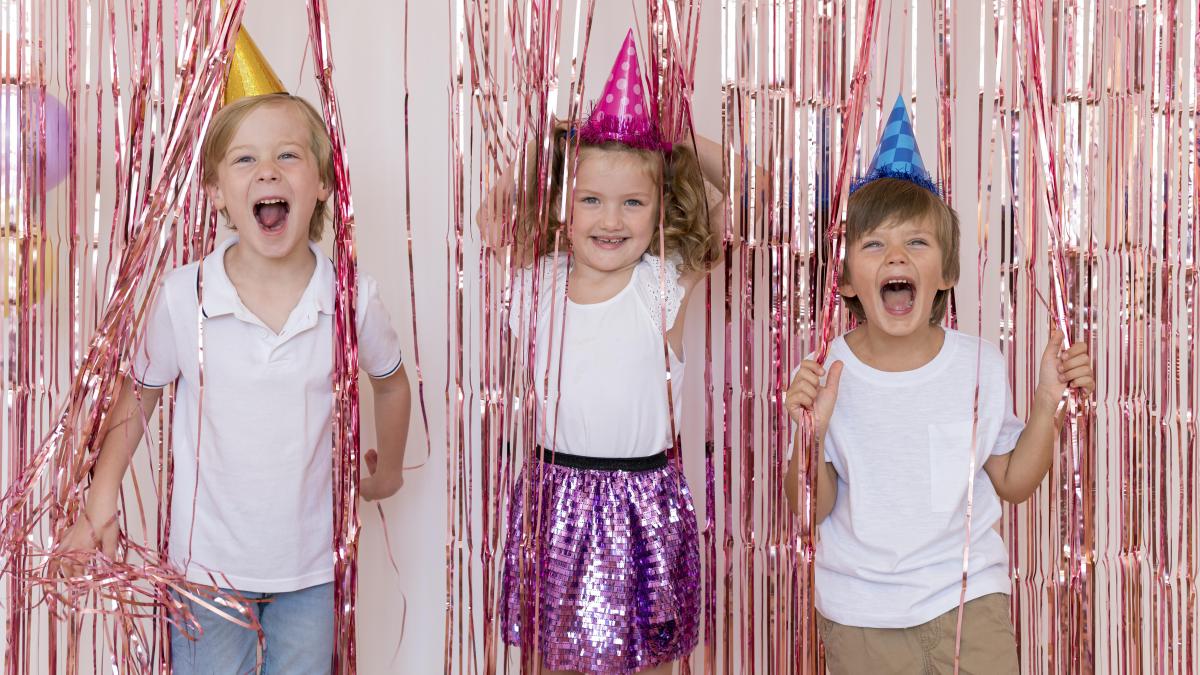 Kids in party hats surrounded by confetti.